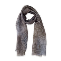 Hand-painted Otta pure linen scarf in 
brown, gray and blue, loosely looped to showcase its full length and delicate texture in white background. Lightweight artisan accessory with hand-sewn edges, measuring 51x 202 cm.
