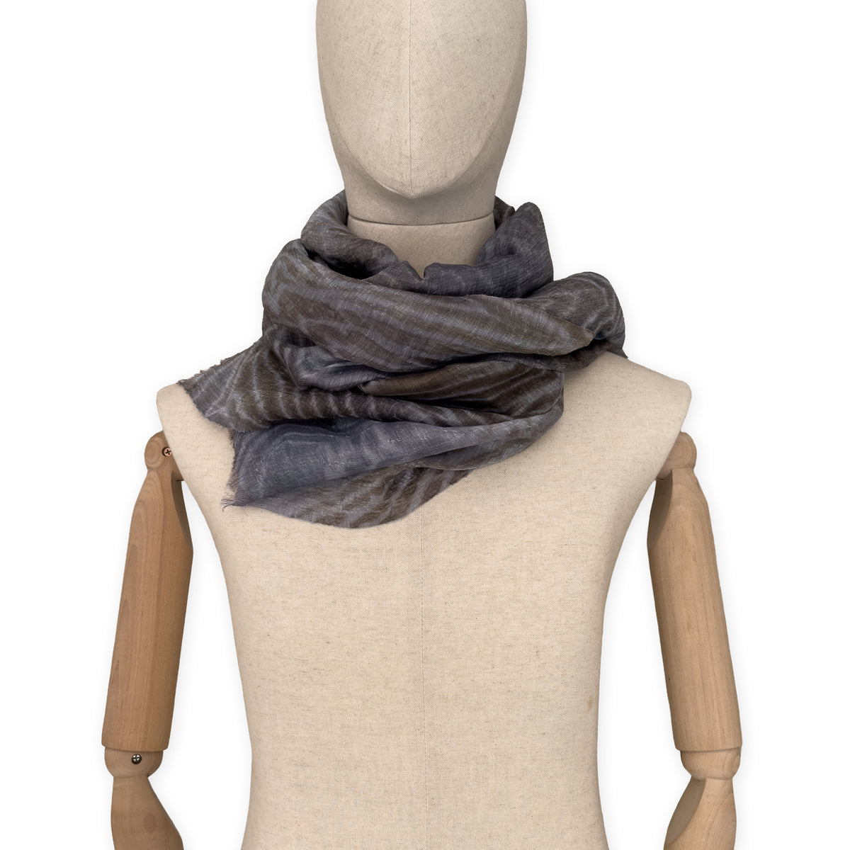 
Mannequin wearing a hand-painted Otta pure linen scarf on a white background in 
brown, gray and blue tones. soft, fresh and lightweight, and elegant accessory measuring 51x 202 cm. Unique artisan scarf with hand-sewn edges, perfect for women and men.
