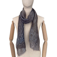
Mannequin wearing a hand-painted Otta pure linen scarf on a white background in 
brown, gray and blue tones. soft, fresh and lightweight, and elegant accessory measuring 51x 202 cm. Unique artisan scarf with hand-sewn edges, perfect for women and men.

