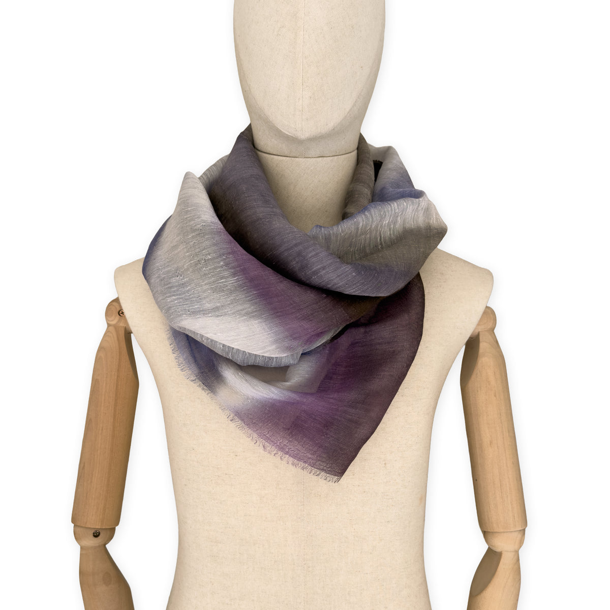 Mannequin wearing an elegant hand-painted Otta linen silk blend scarf on a white background. Indigo, light blue, purple, brown and beige tones.
