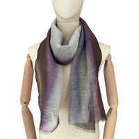 Mannequin wearing an elegant hand-painted Otta linen silk blend scarf on a white background. Indigo, light blue, purple, brown and beige tones.
