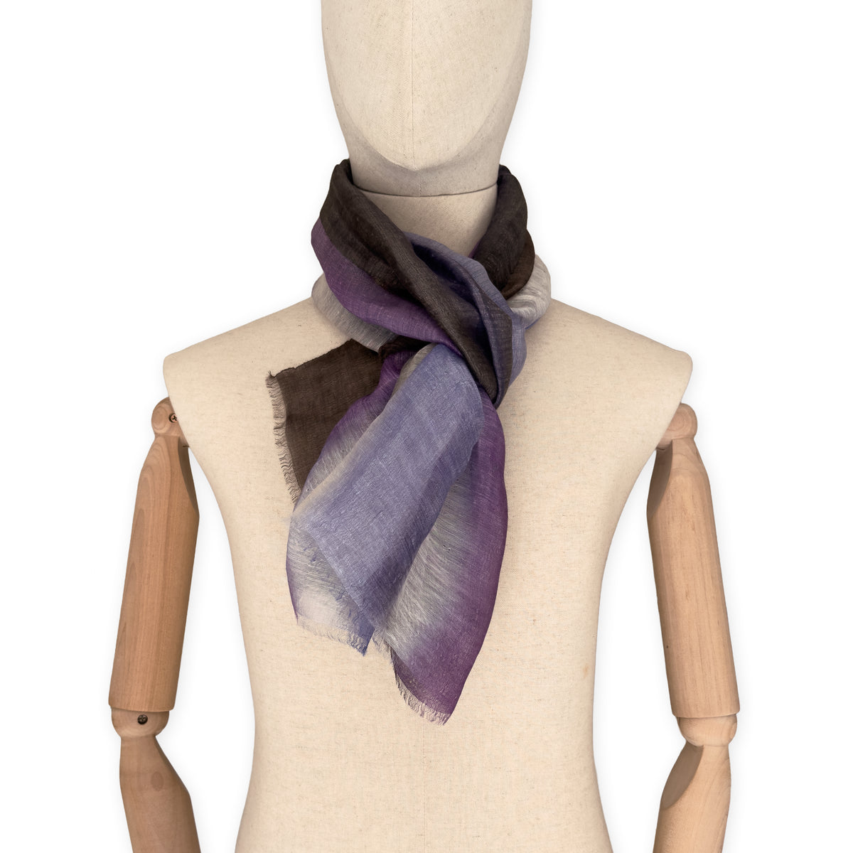 Mannequin wearing an elegant hand-painted Otta linen silk blend scarf on a white background. Indigo, light blue, purple, brown and beige tones.
