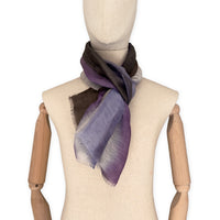Mannequin wearing an elegant hand-painted Otta linen silk blend scarf on a white background. Indigo, light blue, purple, brown and beige tones.
