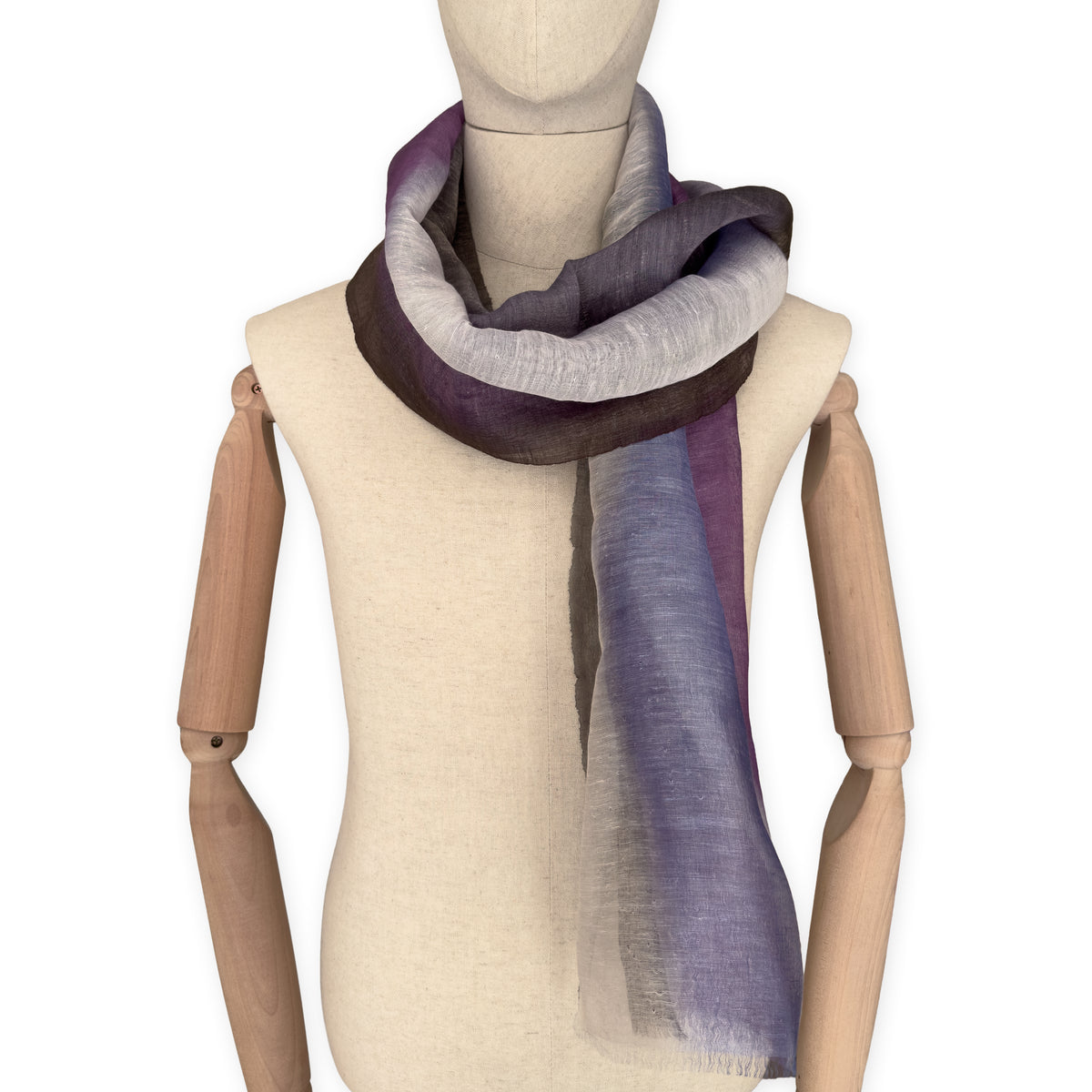 Mannequin wearing an elegant hand-painted Otta linen silk blend scarf on a white background. Indigo, light blue, purple, brown and beige tones.
