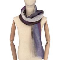 Mannequin wearing an elegant hand-painted Otta linen silk blend scarf on a white background. Indigo, light blue, purple, brown and beige tones.
