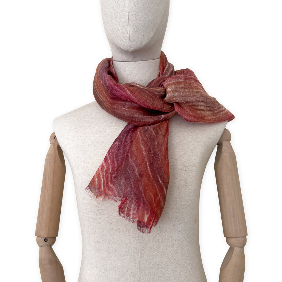 Mannequin wearing a hand-painted Otta pure linen scarf on a white background in 
brown and red tones. soft, fresh and lightweight, and elegant accessory measuring 203 x 50 cm. Unique artisan scarf with hand-sewn edges, perfect for women and men.
