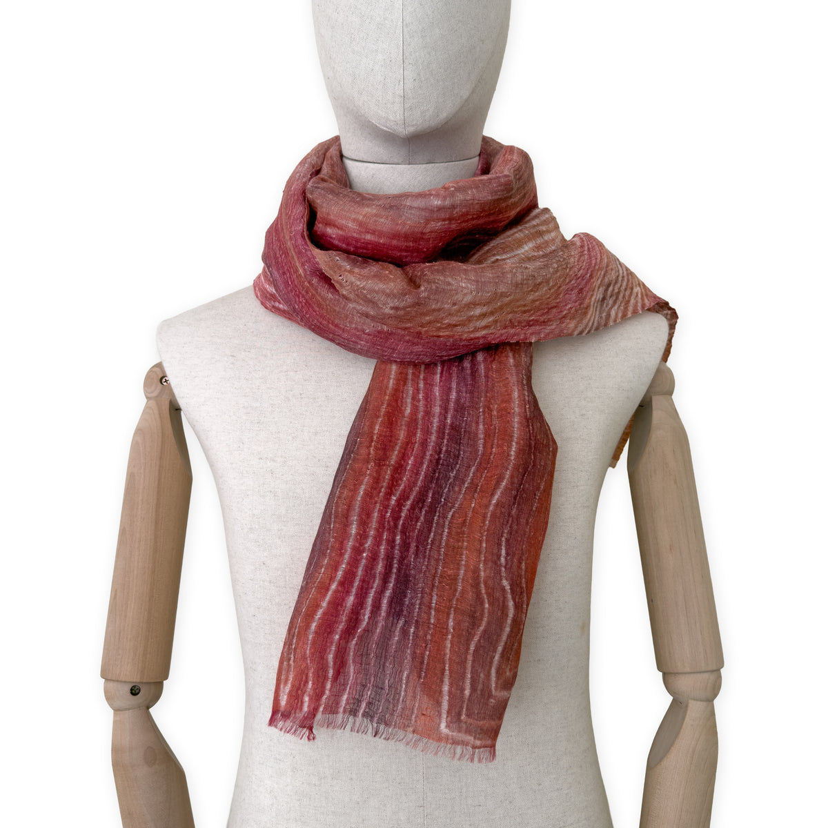 Mannequin wearing a hand-painted Otta pure linen scarf on a white background in 
brown and red tones. soft, fresh and lightweight, and elegant accessory measuring 203 x 50 cm. Unique artisan scarf with hand-sewn edges, perfect for women and men.

