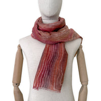 Mannequin wearing a hand-painted Otta pure linen scarf on a white background in 
brown and red tones. soft, fresh and lightweight, and elegant accessory measuring 203 x 50 cm. Unique artisan scarf with hand-sewn edges, perfect for women and men.
