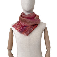 Mannequin wearing a hand-painted Otta pure linen scarf on a white background in 
brown and red tones. soft, fresh and lightweight, and elegant accessory measuring 203 x 50 cm. Unique artisan scarf with hand-sewn edges, perfect for women and men.
