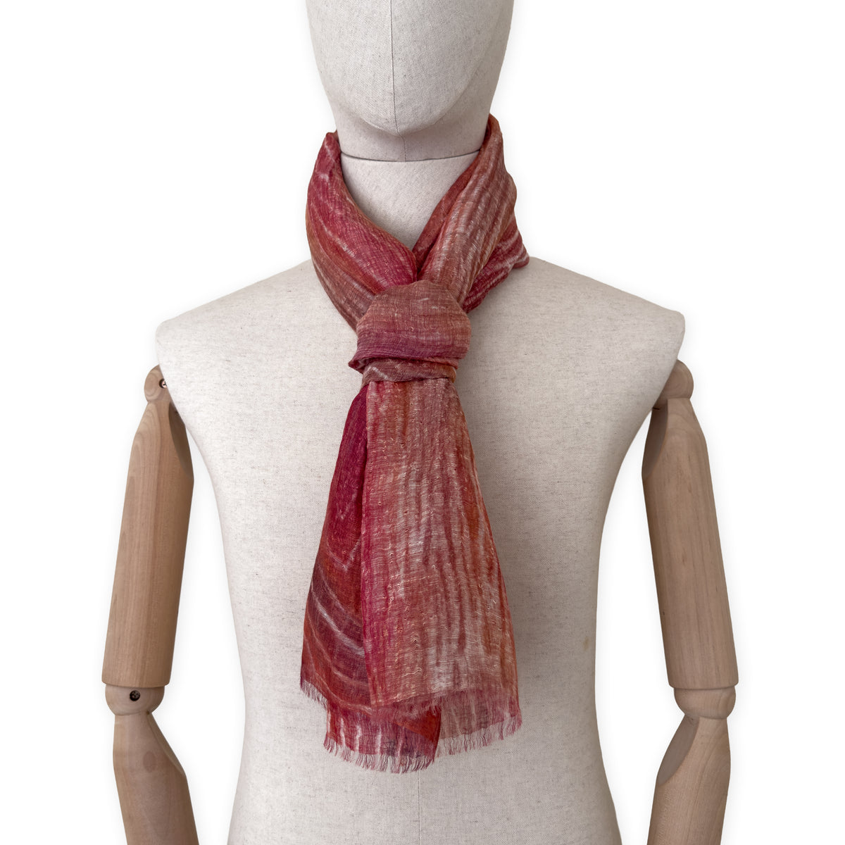 Mannequin wearing a hand-painted Otta pure linen scarf on a white background in 
brown and red tones. soft, fresh and lightweight, and elegant accessory measuring 203 x 50 cm. Unique artisan scarf with hand-sewn edges, perfect for women and men.
