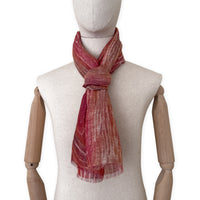 Mannequin wearing a hand-painted Otta pure linen scarf on a white background in 
brown and red tones. soft, fresh and lightweight, and elegant accessory measuring 203 x 50 cm. Unique artisan scarf with hand-sewn edges, perfect for women and men.
