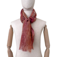 Mannequin wearing a hand-painted Otta pure linen scarf on a white background in 
brown and red tones. soft, fresh and lightweight, and elegant accessory measuring 203 x 50 cm. Unique artisan scarf with hand-sewn edges, perfect for women and men.
