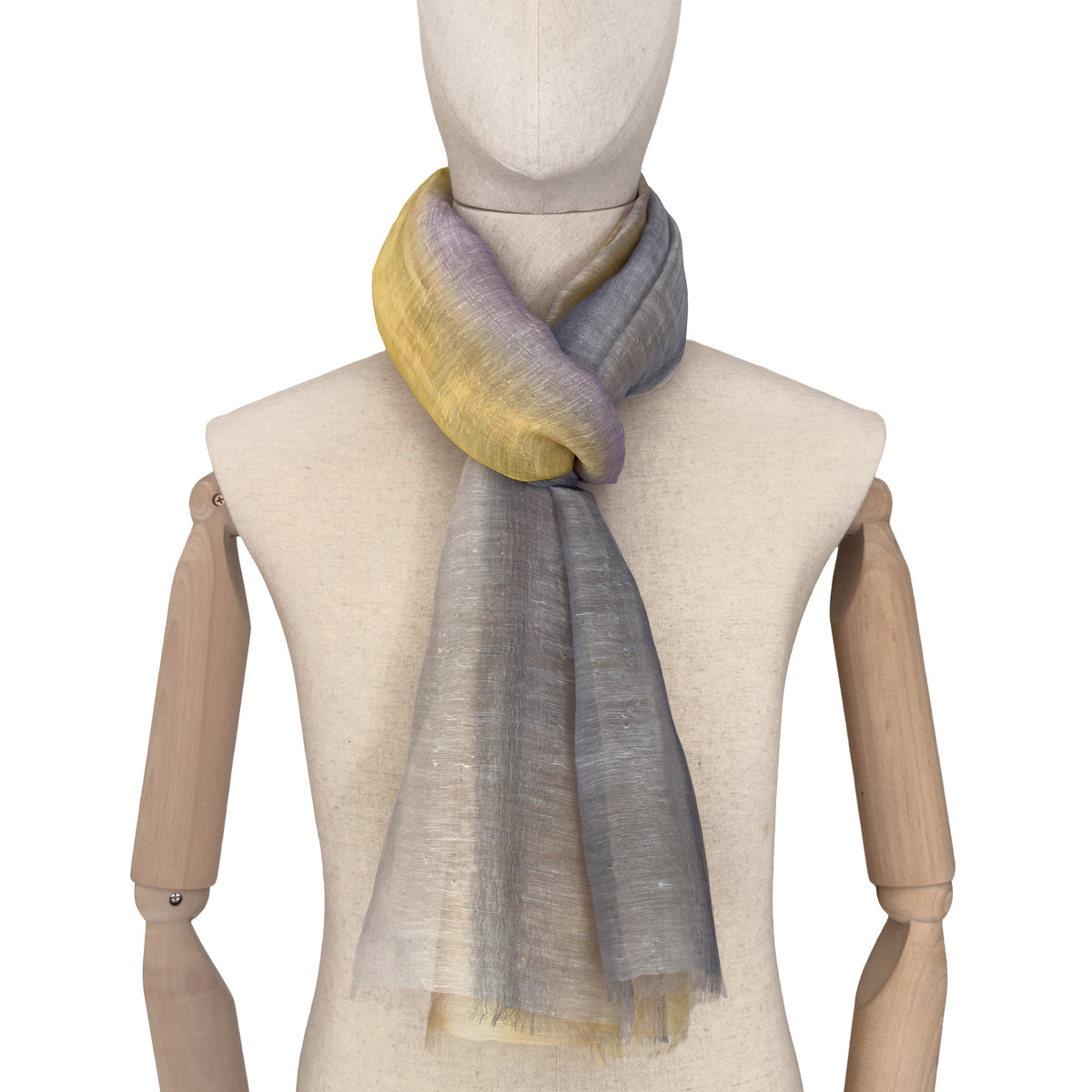 Mannequin wearing an elegant hand-painted Otta-Italy linen silk blend scarf on a white background. Yellow, ochre, sapphire, and gray tones.
