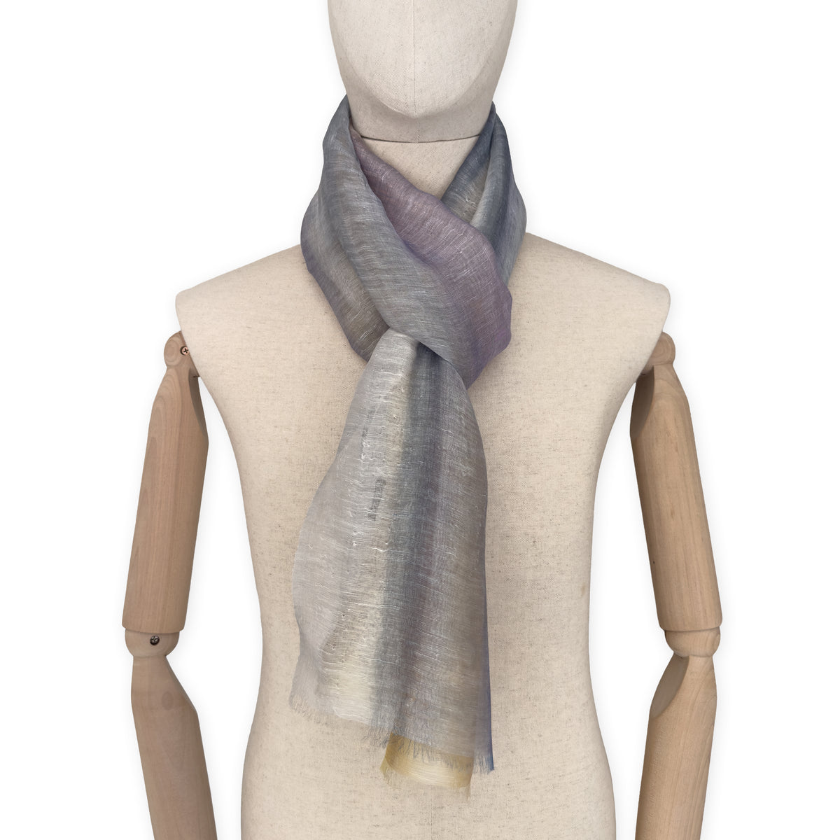 Mannequin wearing an elegant hand-painted Otta-Italy linen silk blend scarf on a white background. Yellow, ochre, sapphire, and gray tones.

