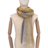 Mannequin wearing an elegant hand-painted Otta-Italy linen silk blend scarf on a white background. Yellow, ochre, sapphire, and gray tones.


