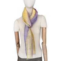 Mannequin wearing a hand-painted Otta pure linen scarf on a white background in 
yellow, purple and lilac tones. soft, fresh and lightweight, and elegant accessory measuring 52 x 200 cm. Unique artisan scarf with hand-sewn edges, perfect for women and men.
