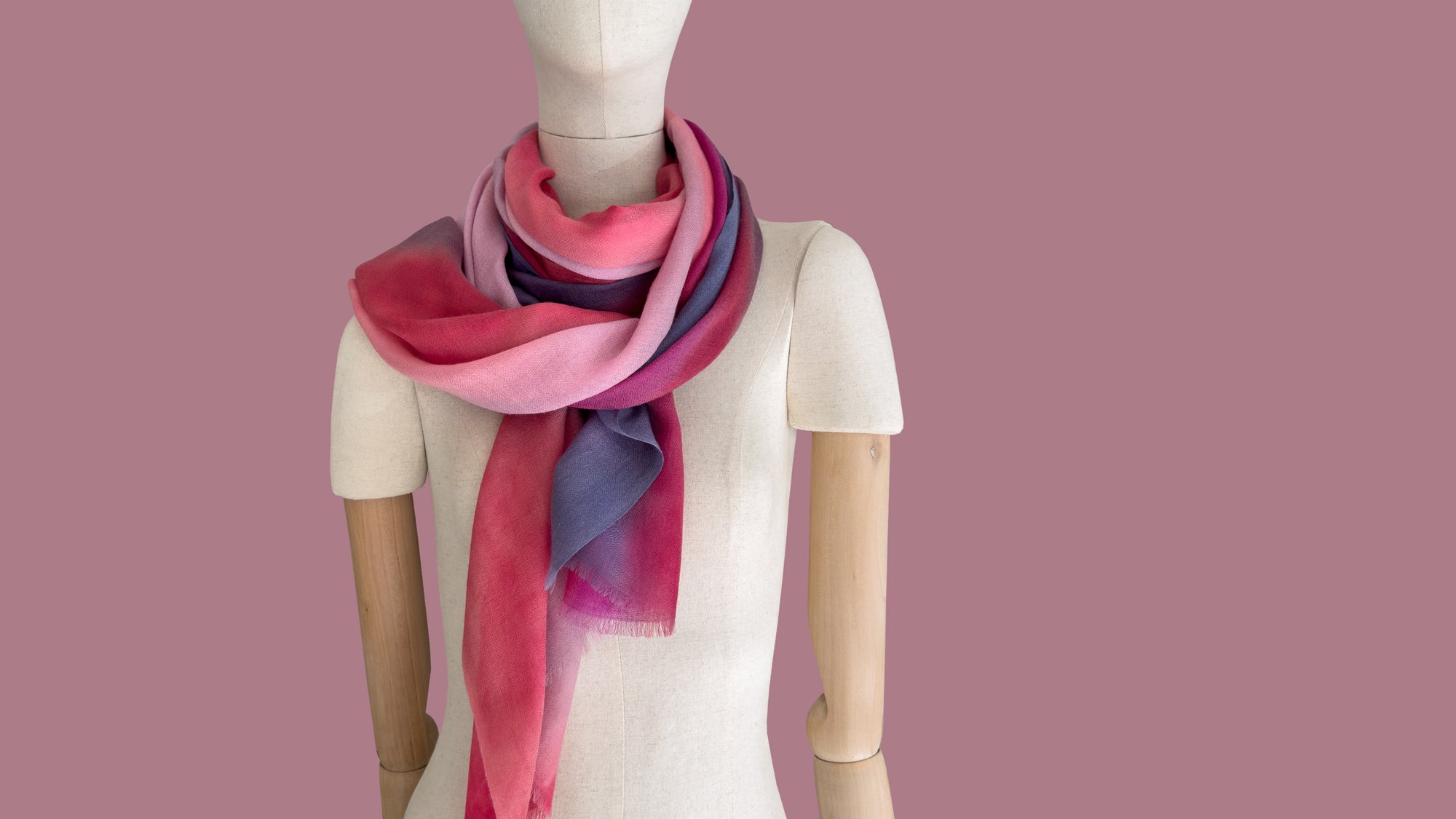 Mannequin wearing scarf on a white background. Hand-painted pure cashmere scarf by Otta-Italy, 66 x 198 cm, featuring red, pink, fuchsia and purple. Luxury Italian cashmere accessory, soft and warm scarf for women and men.
