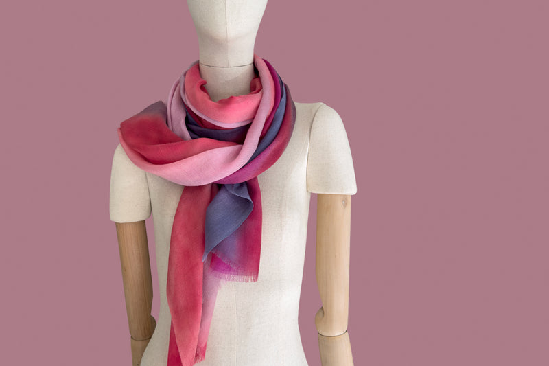 Mannequin wearing scarf on a white background. Hand-painted pure cashmere scarf by Otta-Italy, 66 x 198 cm, featuring red, pink, fuchsia and purple. Luxury Italian cashmere accessory, soft and warm scarf for women and men.
