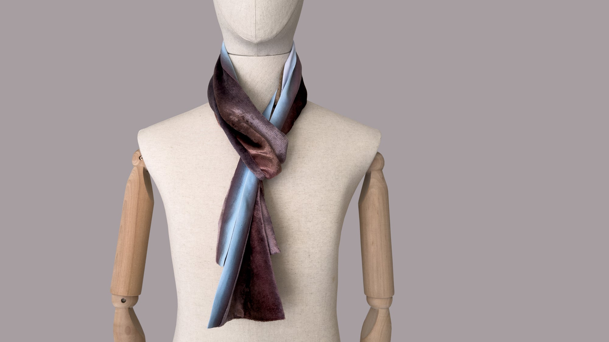 Mannequin wearing a colorful velvet scarf on a white background. Velvet scarf is in shades of brown and blue colors. It is hand-painted scarf in measures 180 x 18 cm by otta-italy scarves brand.
