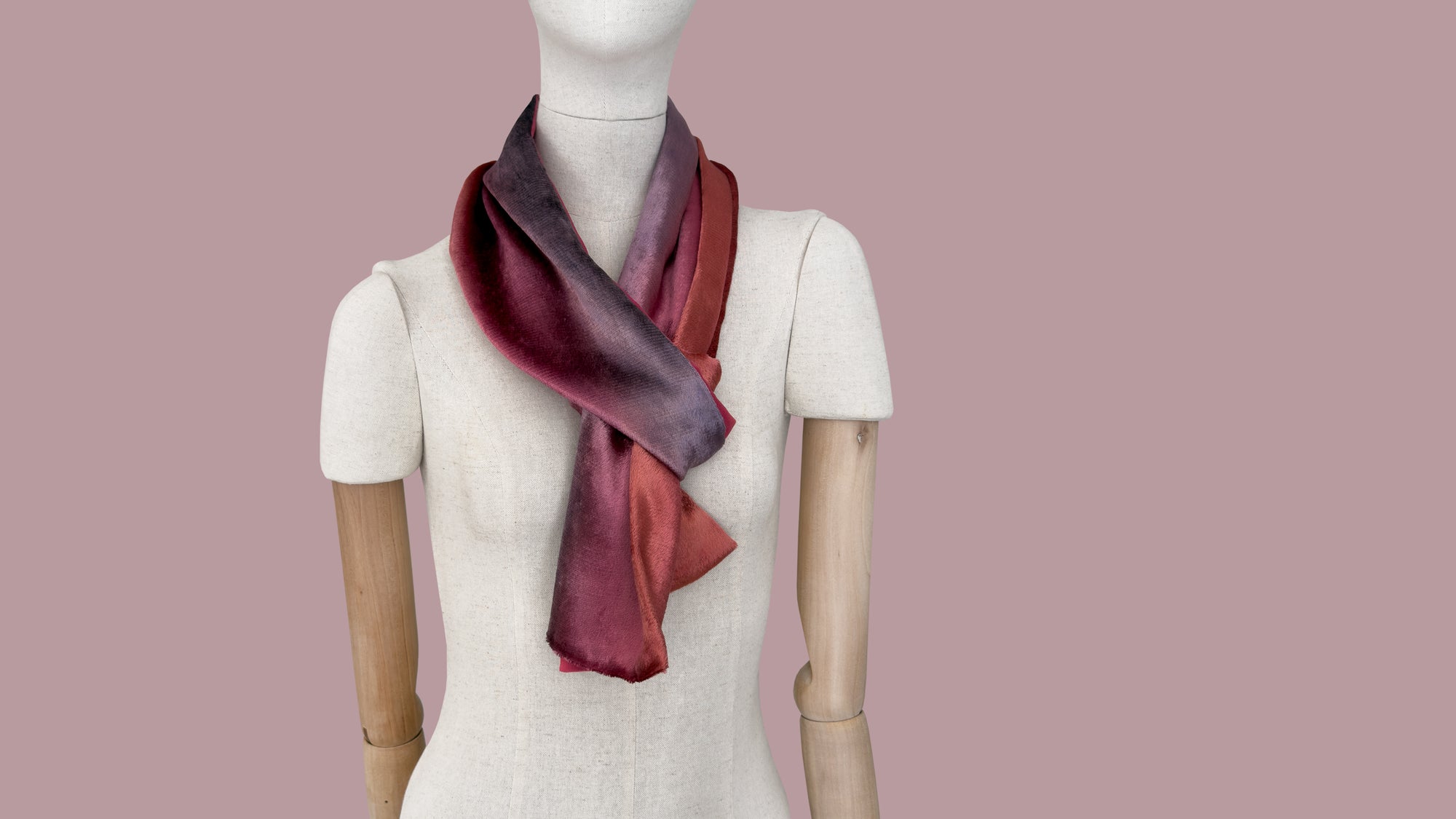 Mannequin wearing a colorful velvet scarf on a white background. Velvet scarf is in shades of red and purple colors. It is hand-painted scarf in measures 184 x 17 cm by otta-italy scarves brand