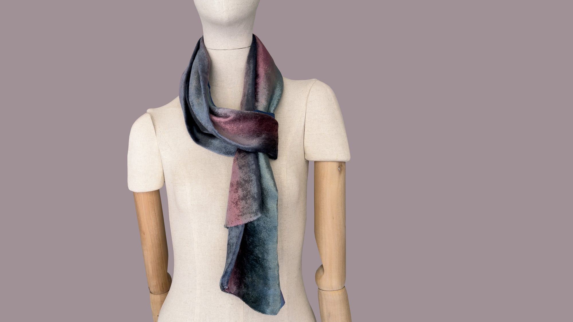 Mannequin wearing a colorful velvet scarf on a white background. Velvet scarf is in shades of green, pink and blue navy colors. It is hand-painted scarf in measures 180 x 20 cm by otta-italy scarves brand.
