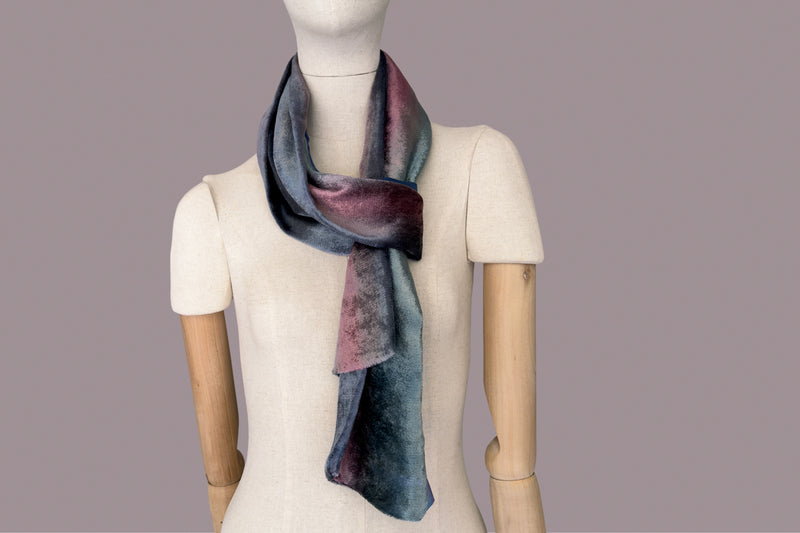 Mannequin wearing a colorful velvet scarf on a white background. Velvet scarf is in shades of green, pink and blue navy colors. It is hand-painted scarf in measures 180 x 20 cm by otta-italy scarves brand.
