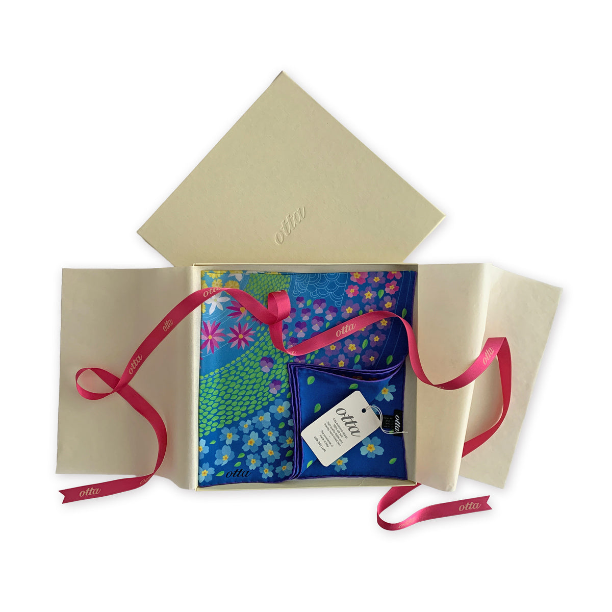 Luxury gift box with a pink ribbon containing an exclusive design Otta silk twill scarf on a white background.
