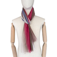 Mannequin wearing a hand-painted Otta silk cotton blend scarf on a white background in 
brown, beige, red and purple tones. soft, fresh and lightweight, and elegant accessory measuring 70 x 190 cm. Unique artisan scarf with hand-fringed edges, perfect for women and men.
