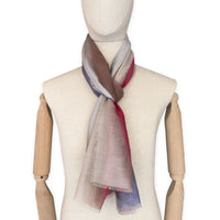 Mannequin wearing a hand-painted Otta silk cotton blend scarf on a white background in 
brown, beige, red and purple tones. soft, fresh and lightweight, and elegant accessory measuring 70 x 190 cm. Unique artisan scarf with hand-fringed edges, perfect for women and men.
