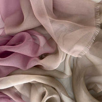 Close-up of a hand-painted Otta pure silk organza scarf showcasing vibrant shades of pink, beige and brown with delicate hand-fringed edges.
