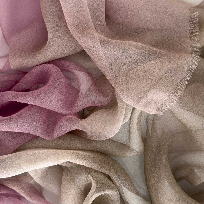 Close-up of a hand-painted Otta pure silk organza scarf showcasing vibrant shades of pink, beige and brown with delicate hand-fringed edges.

