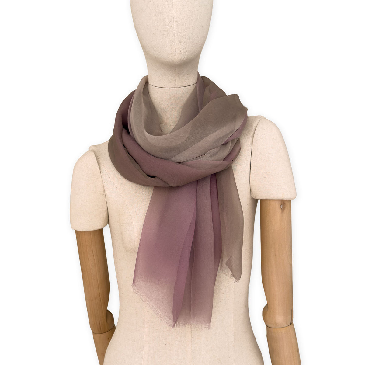 Mannequin wearing an elegant hand-painted Otta pure silk organza scarf on a gray background. Pink, beige and brown tones.
