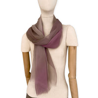 Mannequin wearing an elegant hand-painted Otta pure silk organza scarf on a gray background. Pink, beige and brown tones.
