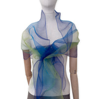 Mannequin wearing an elegant hand-painted Otta pure silk organza scarf on a gray background. Blue, green and violet tones.
