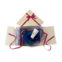 Luxury gift box with a pink ribbon containing a hand-painted Otta pure silk organza scarf on a white background.
