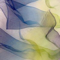 Close-up of a hand-painted Otta pure silk organza scarf showcasing vibrant shades of blue, green and violet with delicate hand-fringed edges.
