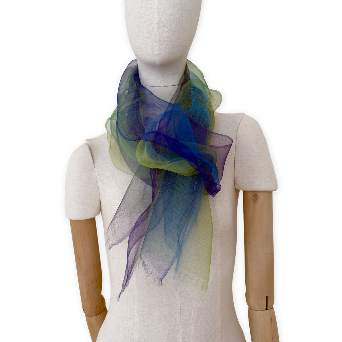Mannequin wearing an elegant hand-painted Otta pure silk organza scarf on a gray background. Blue, green and violet tones.
