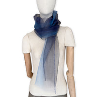 Mannequin wearing a colorful and lightweight silk scarf on a white background. Silk scarf is in shades of gray, midnight blue and blue colors. It is hand-painted scarf in measures 50 x 200 cm by otta-italy scarves brand.
