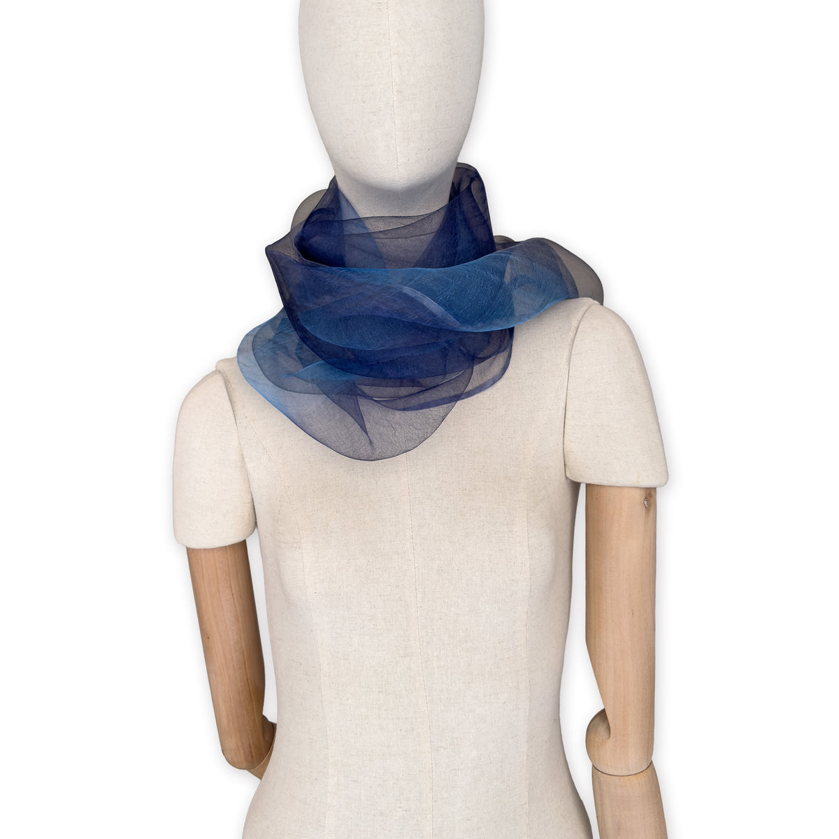 Mannequin wearing a colorful and lightweight silk scarf on a white background. Silk scarf is in shades of gray, midnight blue and blue colors. It is hand-painted scarf in measures 50 x 200 cm by otta-italy scarves brand.
