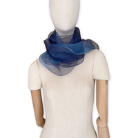 Mannequin wearing a colorful and lightweight silk scarf on a white background. Silk scarf is in shades of gray, midnight blue and blue colors. It is hand-painted scarf in measures 50 x 200 cm by otta-italy scarves brand.
