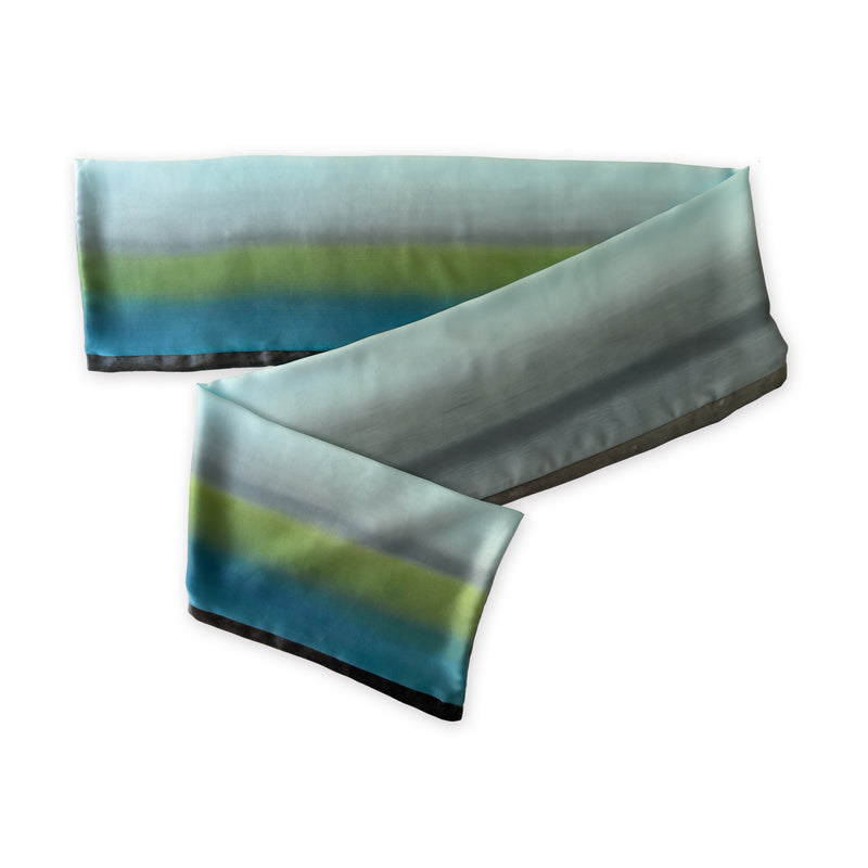 Multicolored silk scarf on a white background. Hand-painted silk scarf by Otta-Italy, 172 x 22 cm, featuring gray, light blue, turquoise and green shades of colors. Luxury Italian silk, soft and lightweight scarf for women and men.

