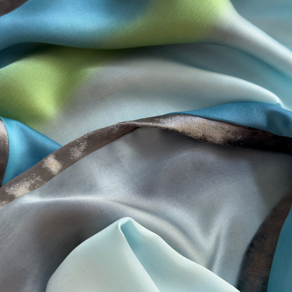 Close-up of fabric. Hand-painted silk scarf by Otta-Italy, 172 x 22 cm, featuring gray, light blue, turquoise and green colors. Luxury Italian silk scarf, soft and lightweight scarf for women and men.
