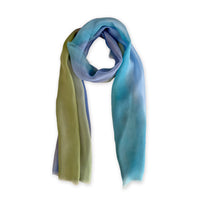 A hand-painted Otta pure silk scarf on a white background, in 
blue, green and gray shades, loosely looped to showcase its full length and delicate texture. Lightweight artisan accessory with hand-fringed edges, measuring 65 x 175 cm.
