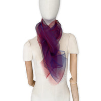 Mannequin wearing a colorful and lightweight silk scarf on a white background. Silk scarf is in shades of red and blue colors. It is hand-painted scarf in measures 48 x 194 cm by otta-italy scarves brand.