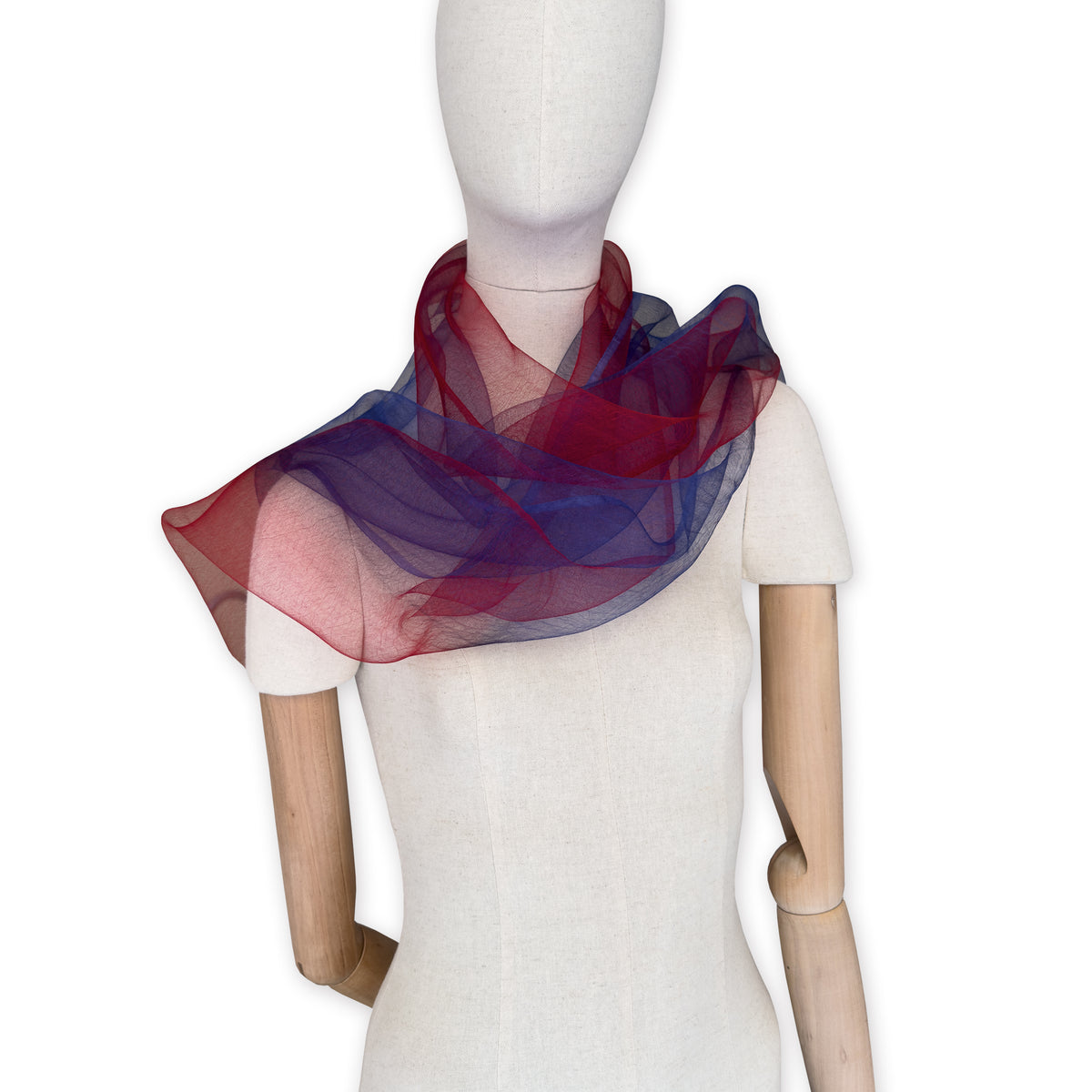 Mannequin wearing a colorful and lightweight silk scarf on a white background. Silk scarf is in shades of red and blue colors. It is hand-painted scarf in measures 48 x 194 cm by otta-italy scarves brand.