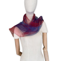 Mannequin wearing a colorful and lightweight silk scarf on a white background. Silk scarf is in shades of red and blue colors. It is hand-painted scarf in measures 48 x 194 cm by otta-italy scarves brand.