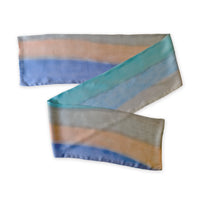 Colorful scarf on a white background. Hand-painted pure silk scarf by Otta-Italy, 45 x 180 cm, featuring 
indigo, turquoise, sky blue, gray and peach. Luxury Italian pure silk accessory, soft and lightweight scarf for women and men.
