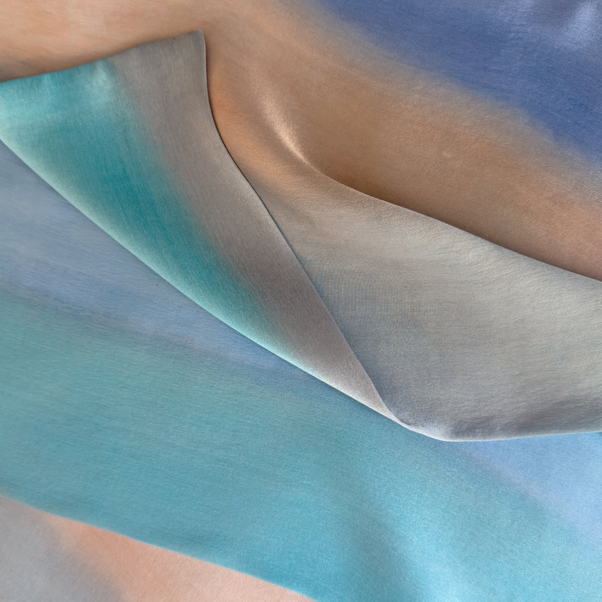 Mannequin wearing scarf on a beige background. Hand-painted silk scarf by Otta-Italy, 45 x 180 cm, featuring 
indigo, turquoise, sky blue, gray and peach. Luxury Italian pure silk accessory, soft and lightweight scarf for women and men.

