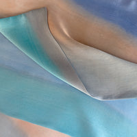 Mannequin wearing scarf on a beige background. Hand-painted silk scarf by Otta-Italy, 45 x 180 cm, featuring 
indigo, turquoise, sky blue, gray and peach. Luxury Italian pure silk accessory, soft and lightweight scarf for women and men.
