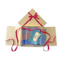 Set of scarves in a gift box with a pink ribbon on a white background. 
Hand-painted silk scarf by Otta-Italy, 45 x 180 cm, featuring 
indigo, turquoise, sky blue, gray and peach. Luxury Italian pure silk accessory, soft and lightweight scarf for women and men.
